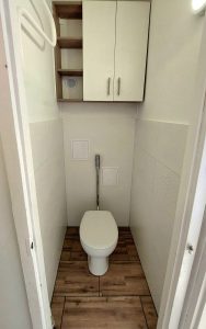 Elkészült, csempézett mellékhelyiség fali WC-vel és felső szekrénnyel